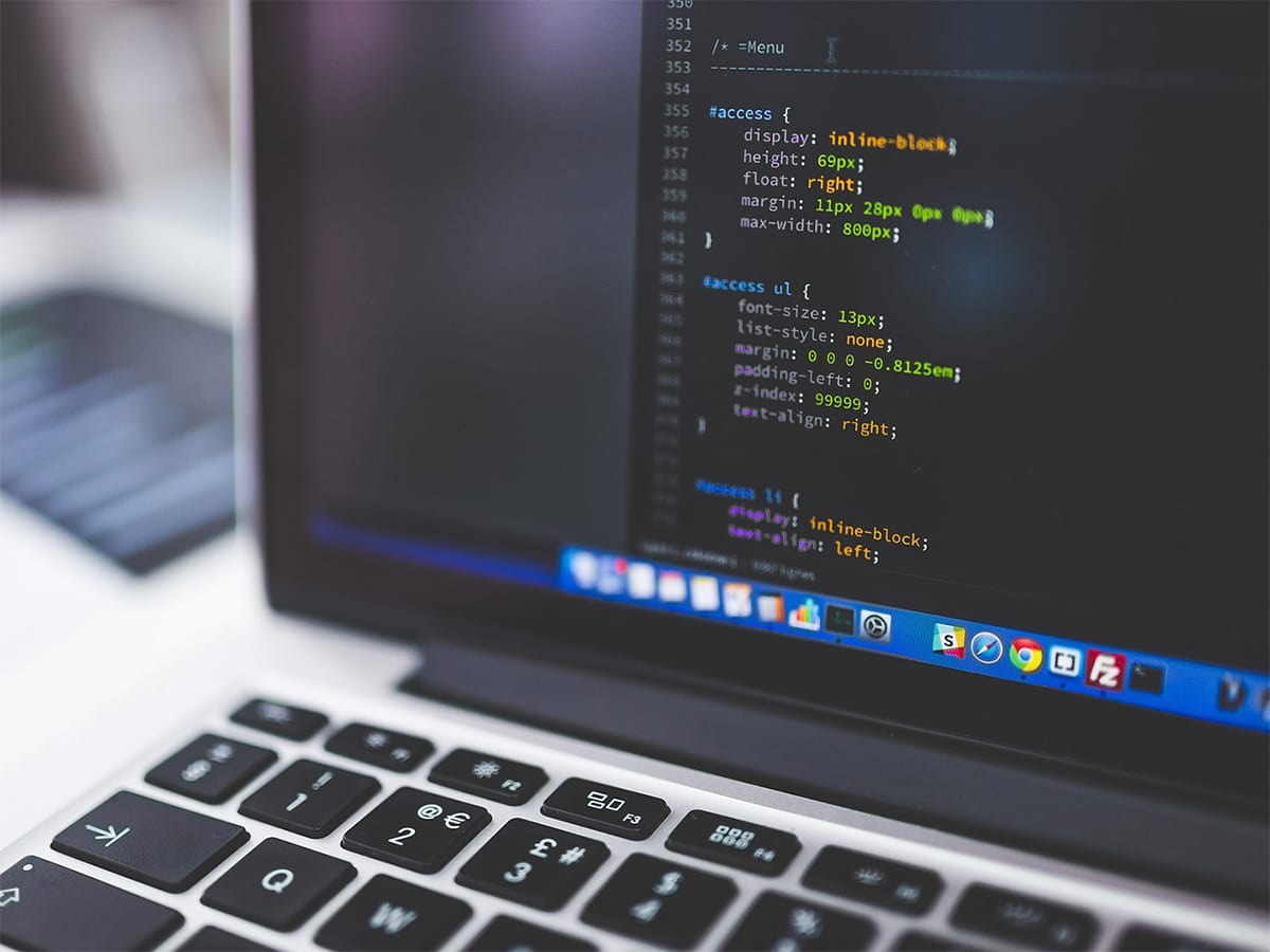 Laptop mit Code auf einem Schreibtisch – Website-Entwicklung für Coaches und Therapeut:innen